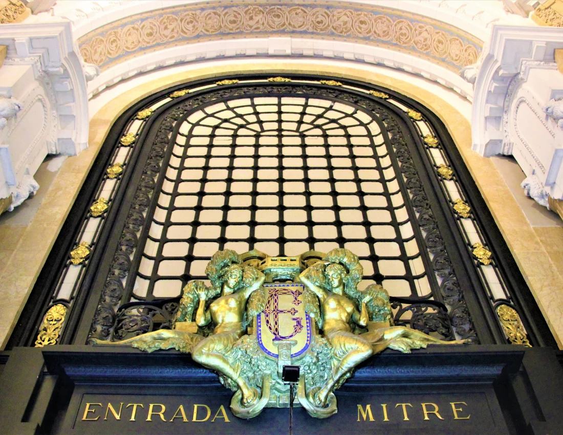 A gilded Art Nouveau archway inside the Galeria Guemes, with a glass-panelled ceiling and bronze figures over the Entrada Mitre doorway